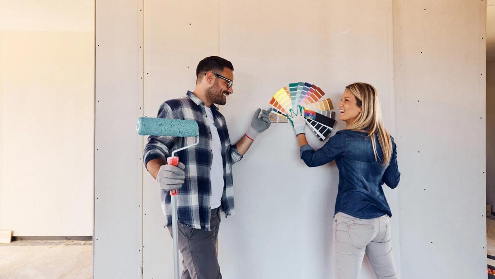 Happy couple talking while choosing color for their renovating house. Copy space.