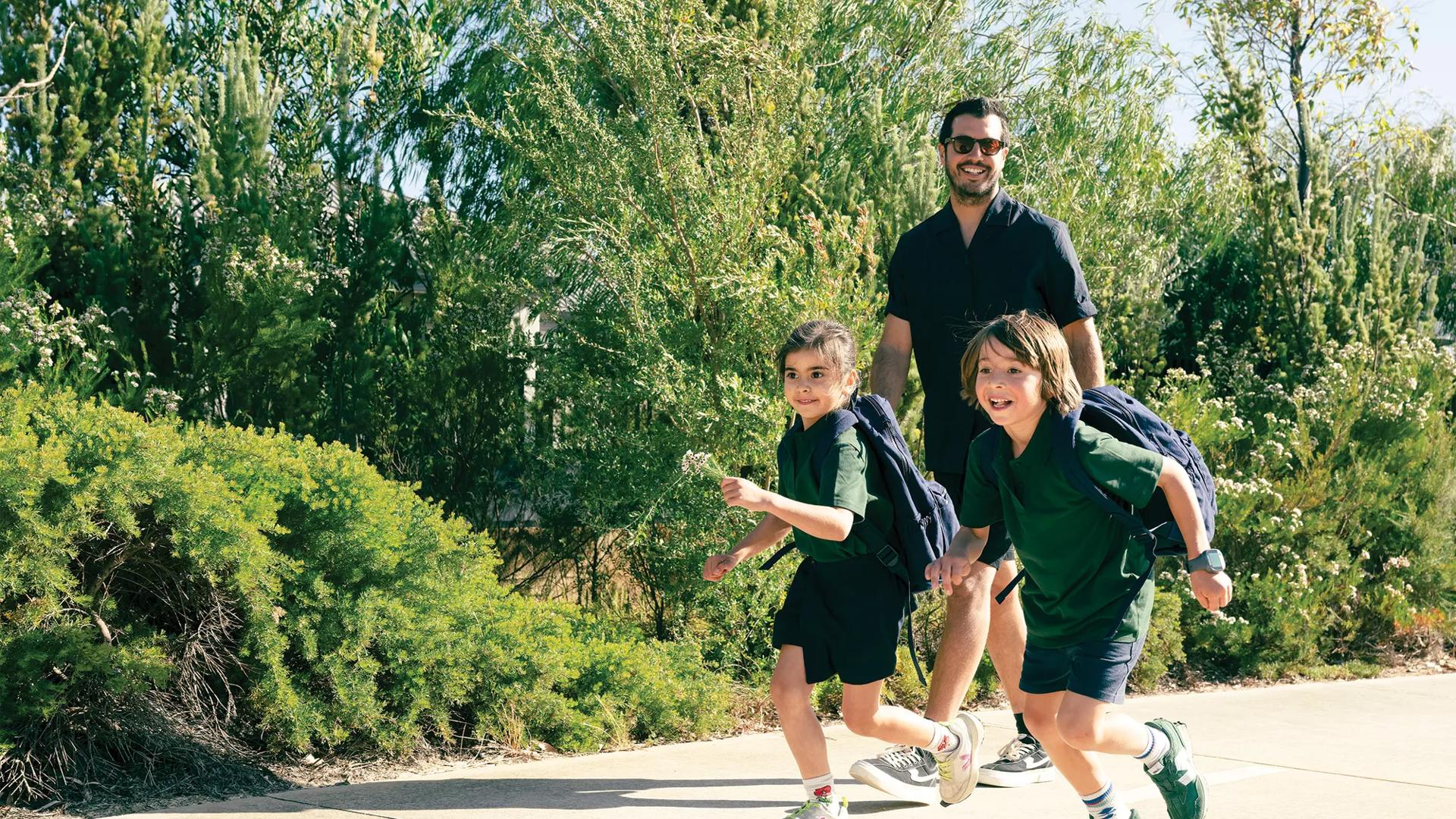 Kids in school uniform running on footpath with Dad